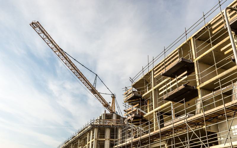 A concrete frame under construction with a tower crane above it
